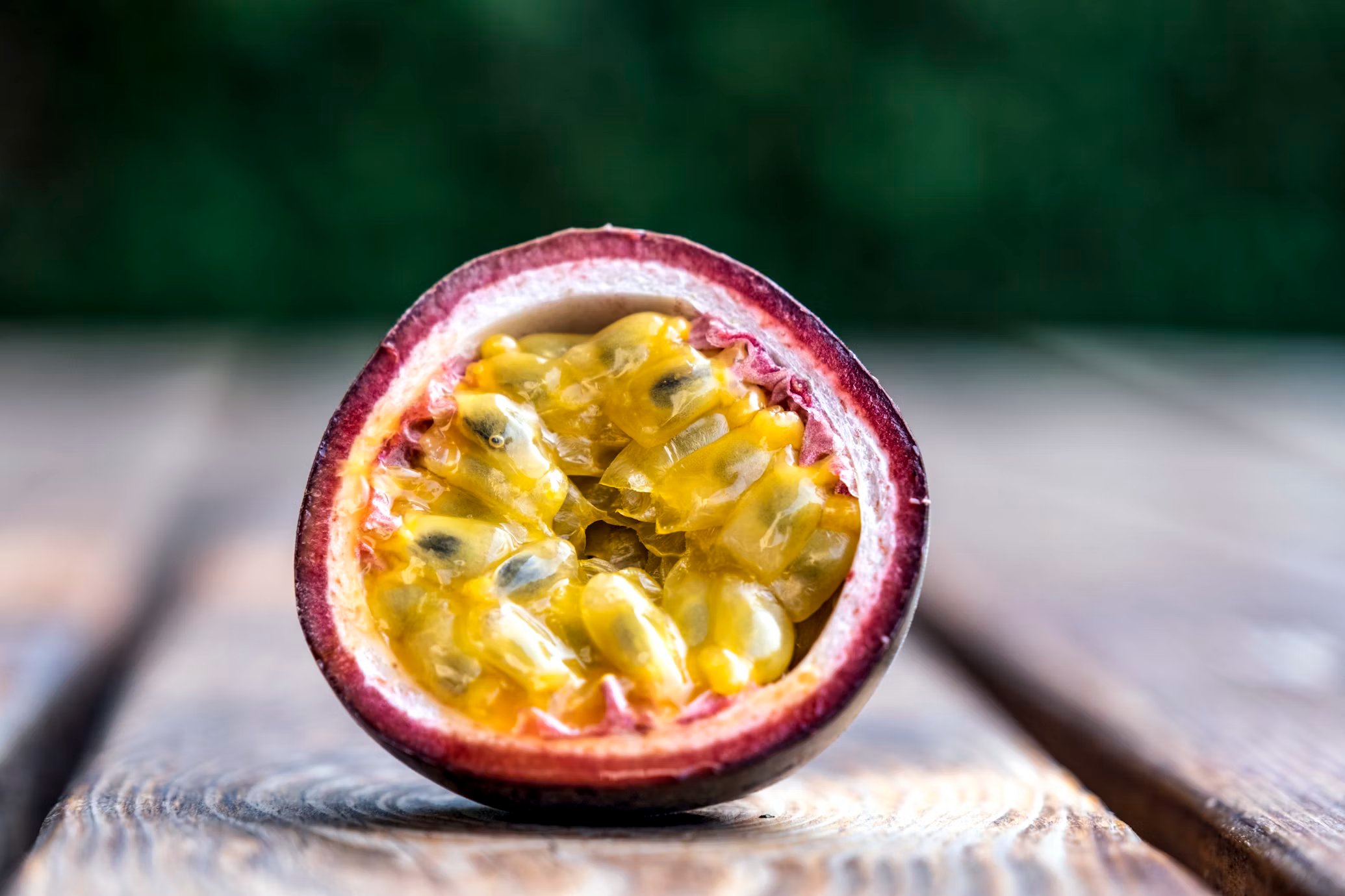 Freshly harvested purple passion fruits, whole and halved, showing the golden aromatic pulp and edible seeds